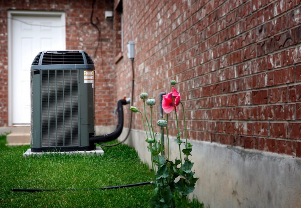 AC unit with flower blooming in foreground