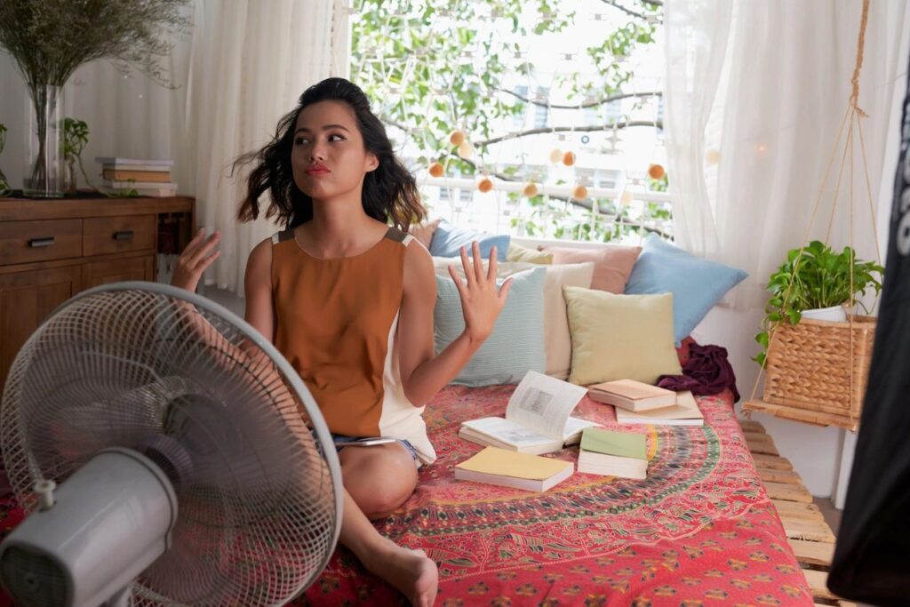 Young woman trying to stay cool by a fan