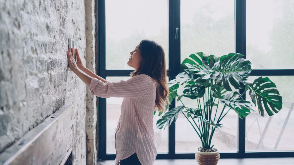 woman adjusting thermostat in Georgia for home during summer